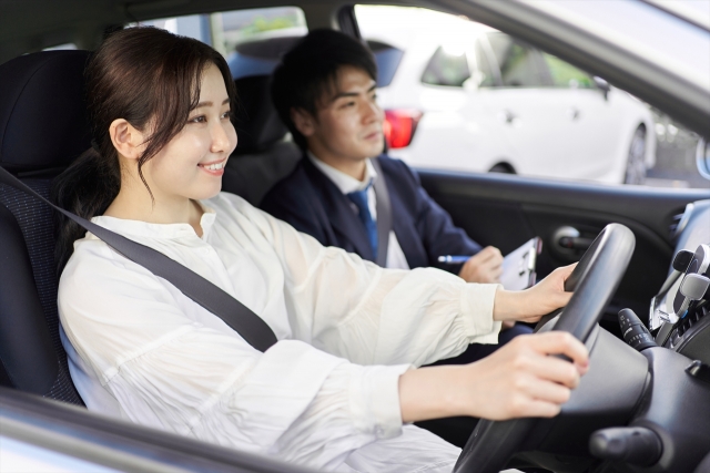 教習車に乗って運転の指導を受ける女性ドライバーと助手席に座って指導をしている教習指導員