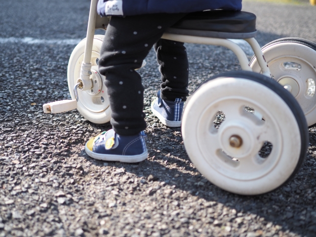 駐車場で三輪車で遊んでいる幼児