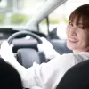 女性が笑顔でAT車オートマチック車を運転している