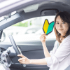 初心者マークをもって車を運転している女性ドライバー