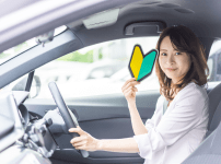 初心者マークをもって車を運転している女性ドライバー