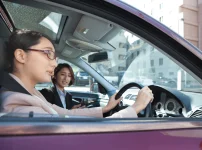 自動車学校で女性教習指導員から技能教習を受けている女性初心者ドライバー