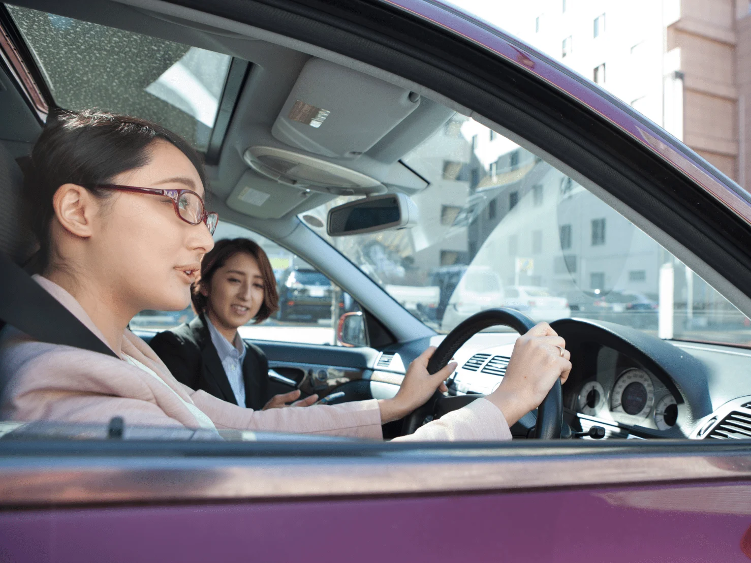 自動車学校で女性教習指導員から技能教習を受けている女性初心者ドライバー